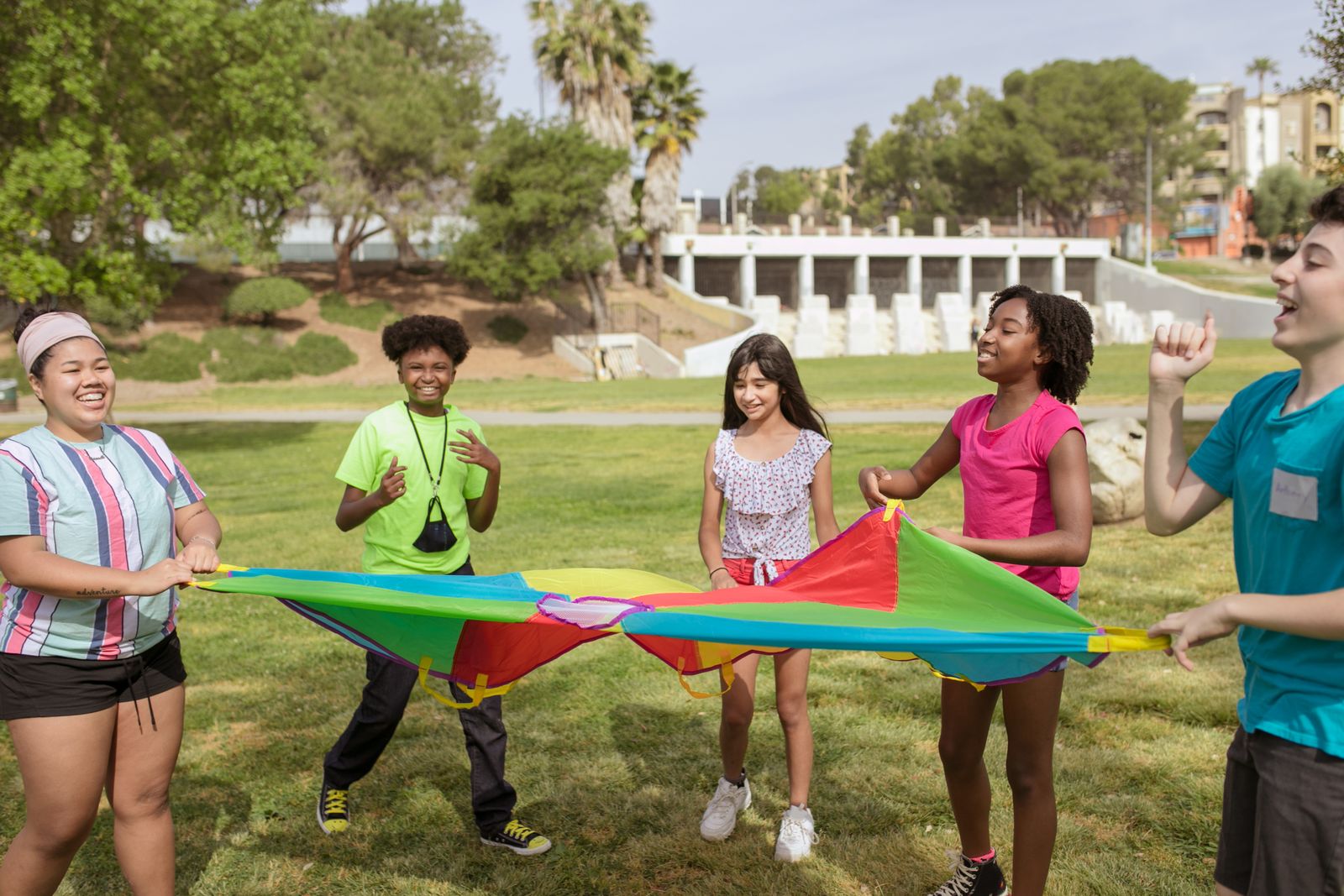 Juegos cooperativos: grupo de niños jugando con un paracaídas de colores